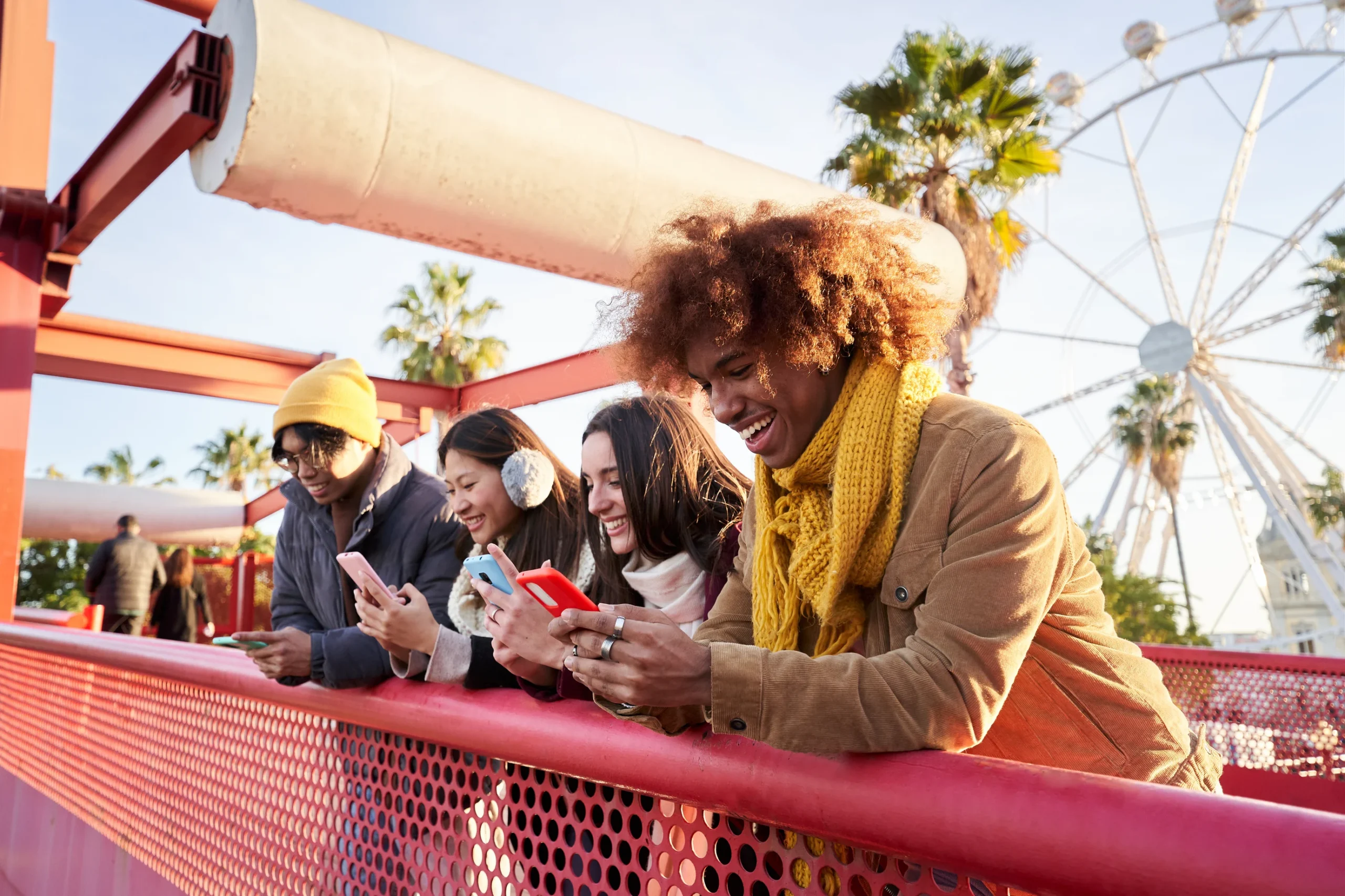 Group of young people using smartphones in queue for theme park ride